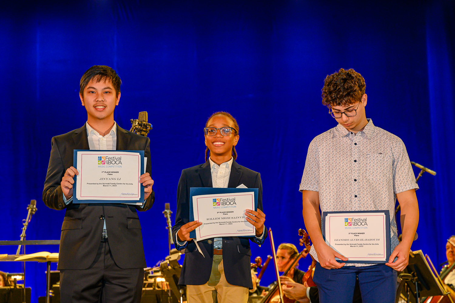 Three boys stand on stage with awards.