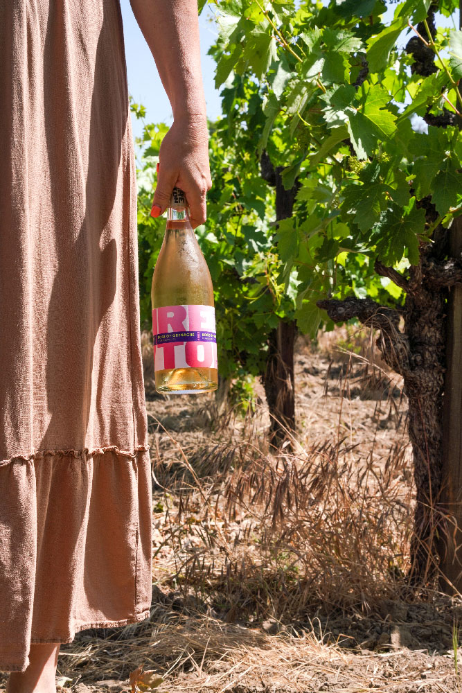 Bottle of wine behind held in vineyard.