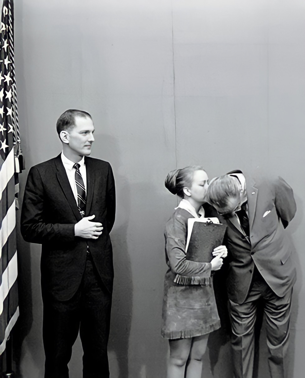 Woman speaking into man's ear.